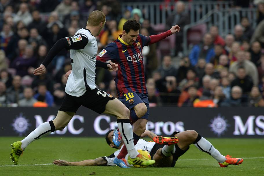 Messi contro i difensori del Valencia. Afp